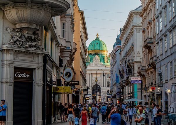 people walking in a busy street between buildings in Vienna