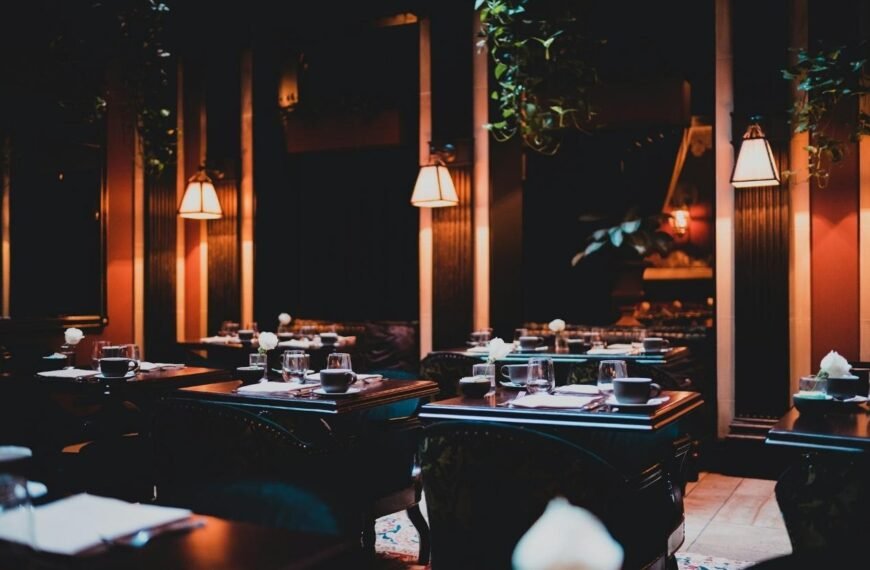 Dimly lit London restaurant dining room with candlelit tables, wine glasses and white roses, evoking the intimate atmosphere of the city's best hidden restaurants